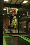 Boy Reaching for Basketball Hoop about to Dunk after Jumping on Trampoline